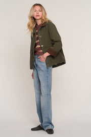 A woman modeling an olive green field jacket with brown trim 