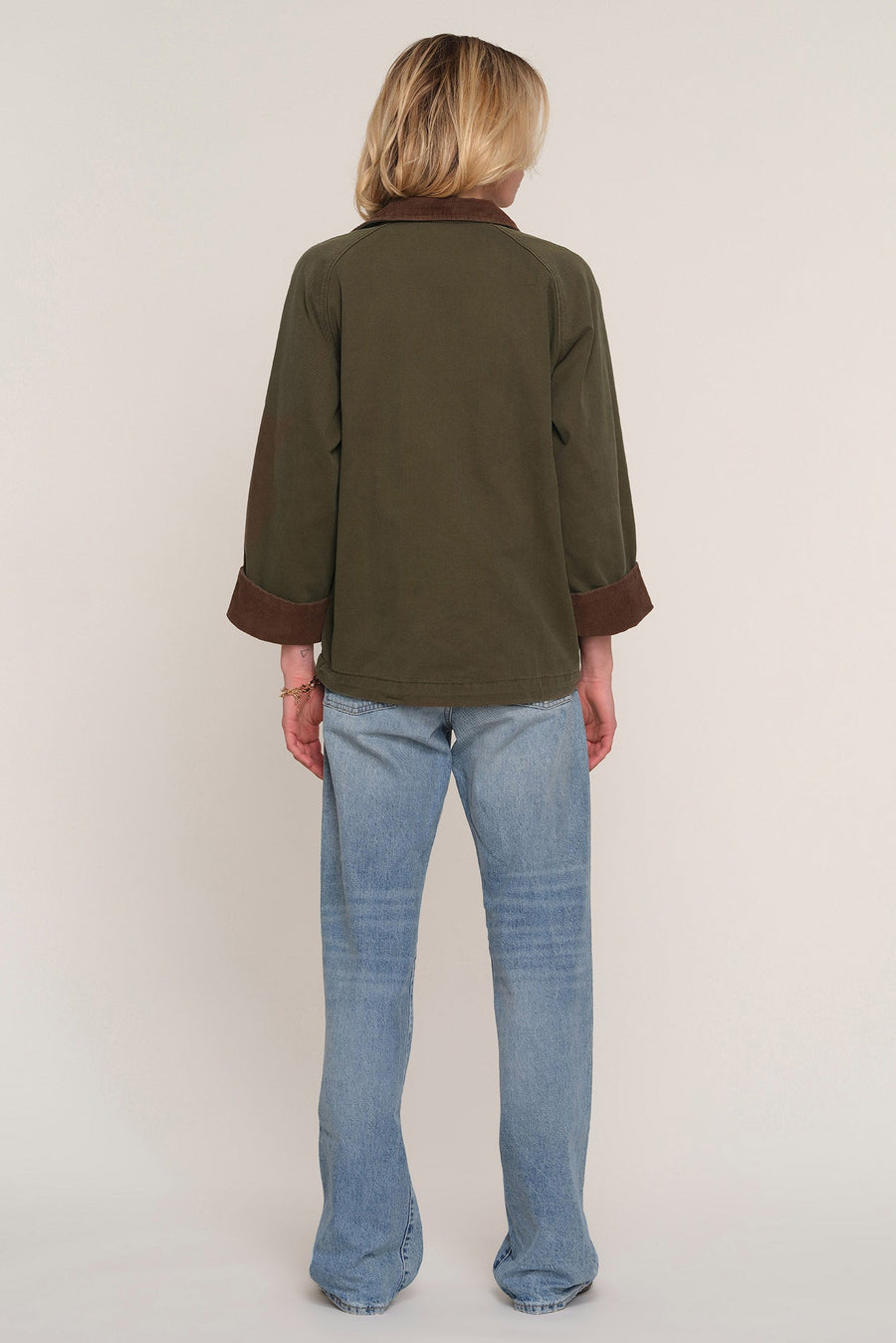 A model shown from the back wearing an olive green long-sleeve shirt with dark brown contrast trim on the collar and cuffs