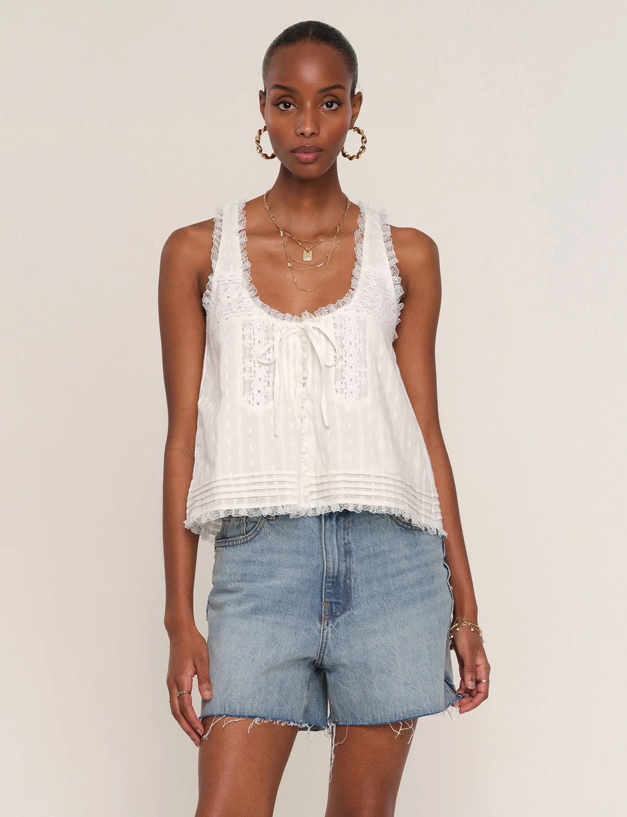 Woman wearing a white sleeveless top with lace detailing. 
