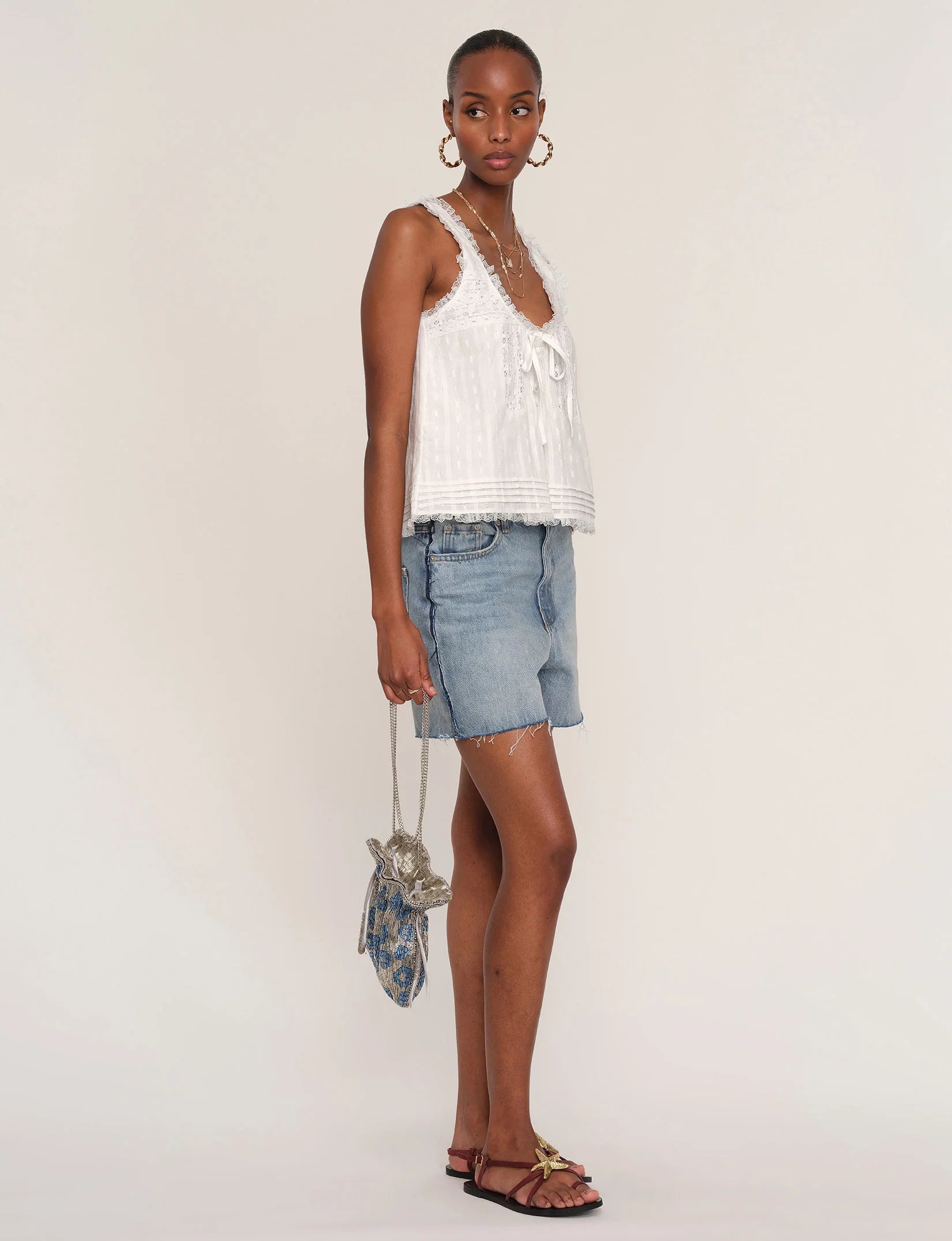 Woman wearing a white sleeveless top with lace detailing. 