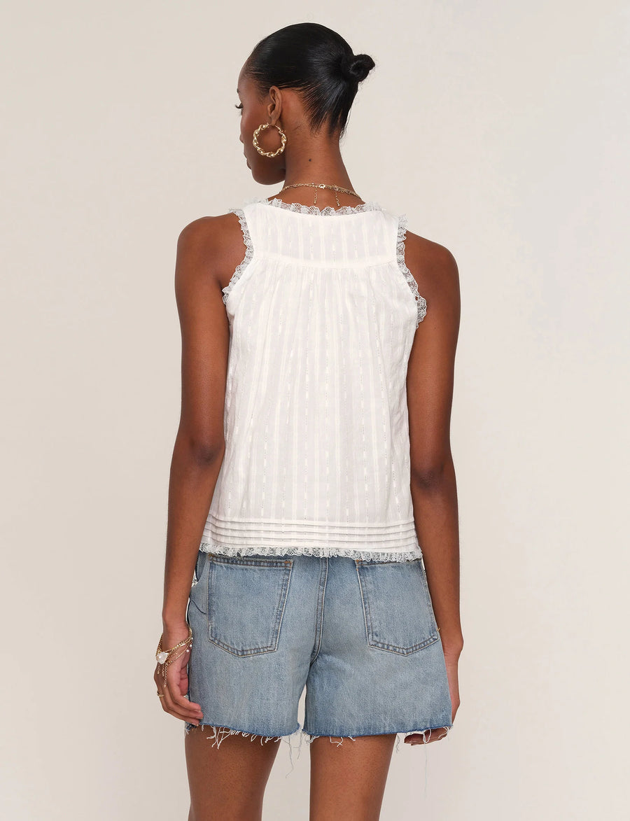 Woman wearing a white sleeveless top with lace detailing. 