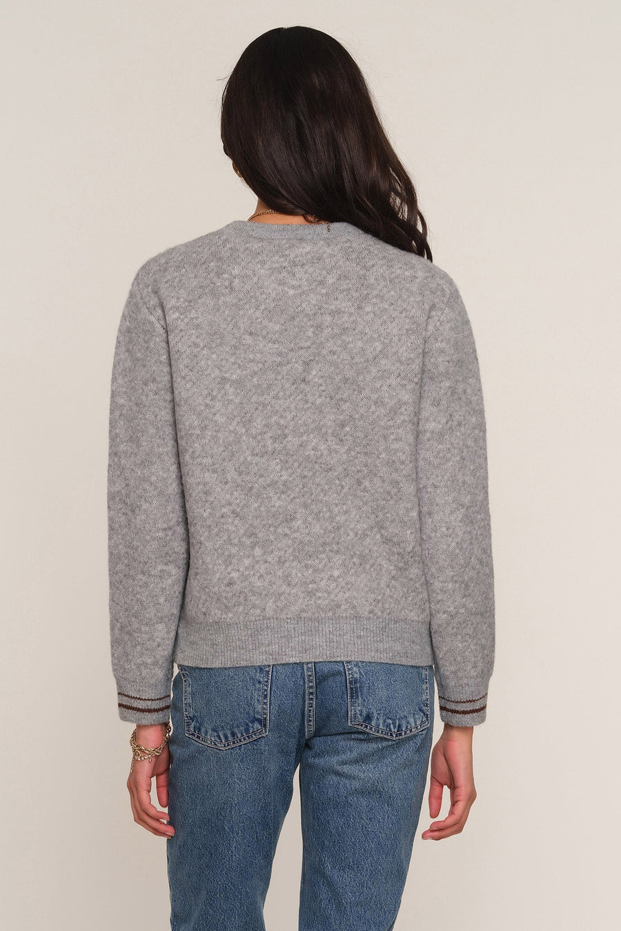 A woman viewed from the back wearing a heather gray crewneck sweate