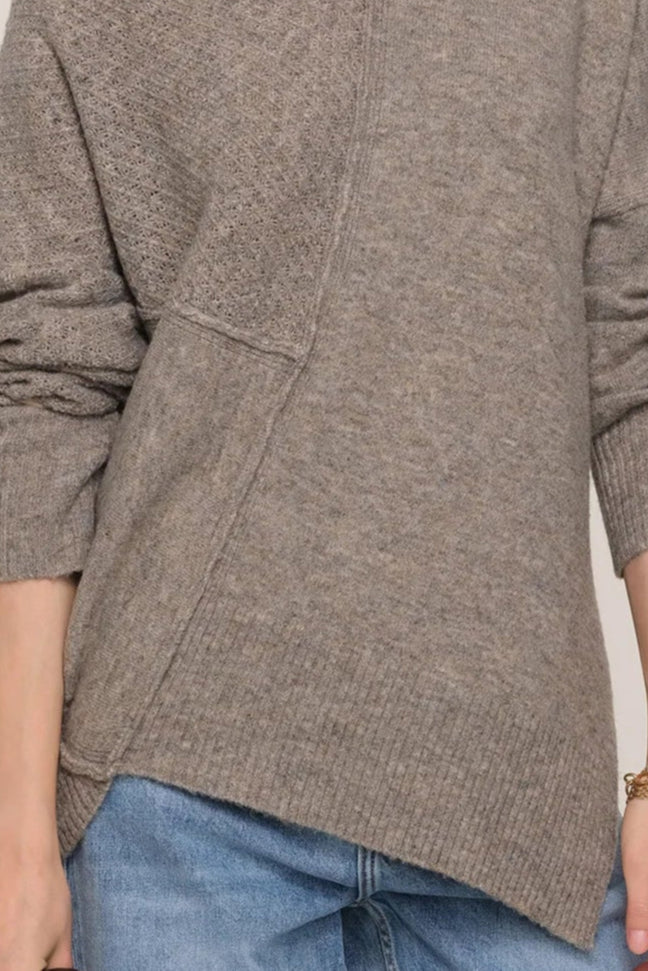 Close-up of woman wearing a greige asymmetrical sweater 