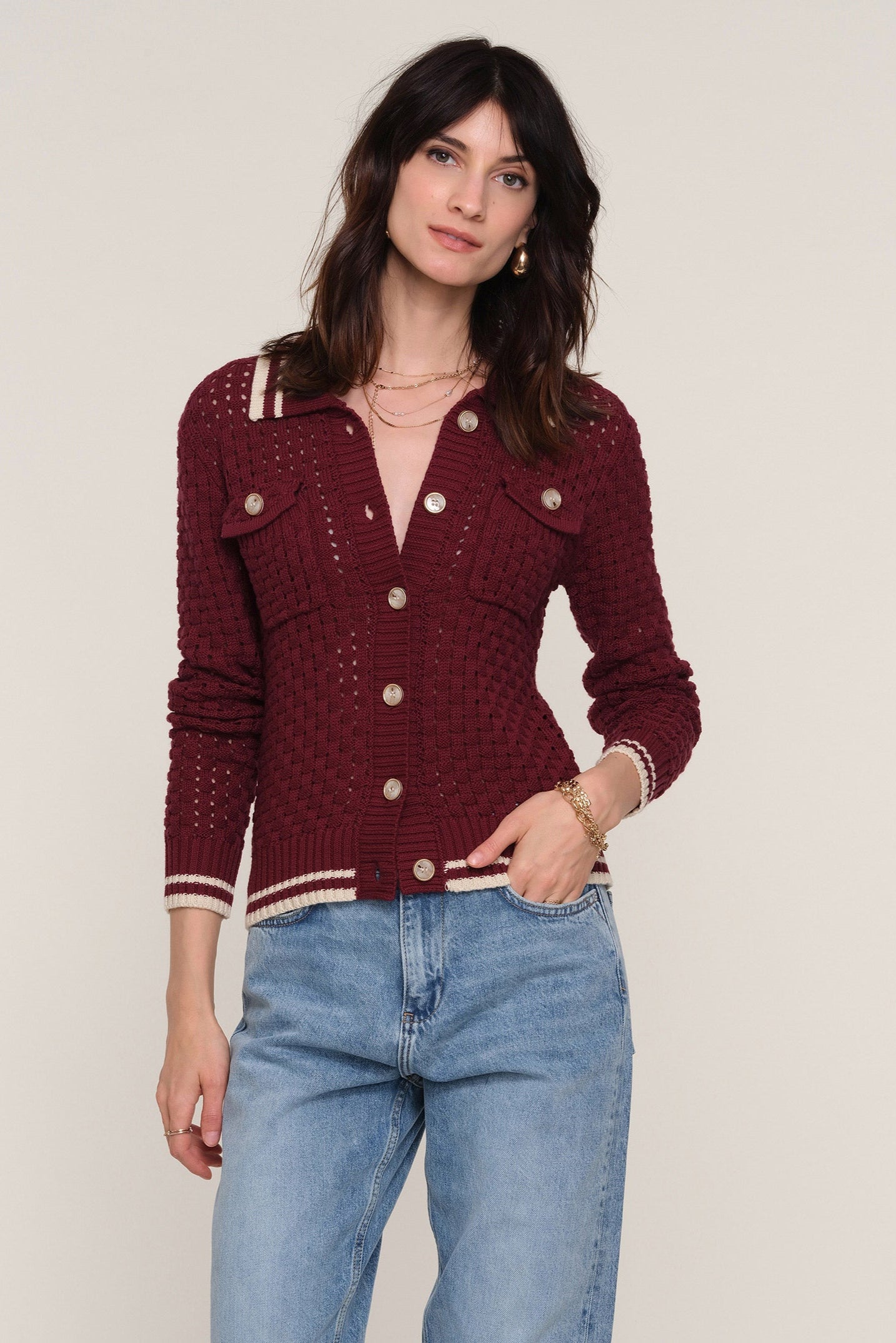 Front view of a woman wearing a wine open-knit cardigan with white trim 