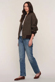 3/4 view of a person wearing a brown checkered bomber jacket and blue jeans