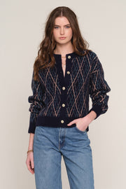 A woman modeling a navy blue knit cardigan with a textured diamond pattern in beige and brown tones, 