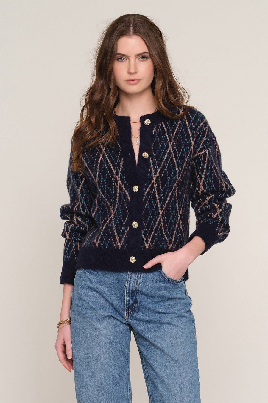 A woman modeling a navy blue knit cardigan with a textured diamond pattern in beige and brown tones, 