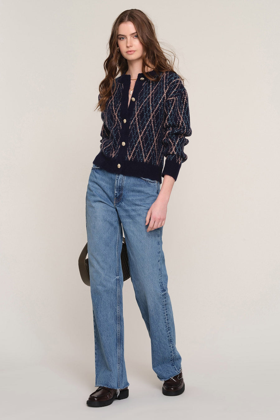 A woman modeling a navy blue knit cardigan with a beige and white diamond pattern