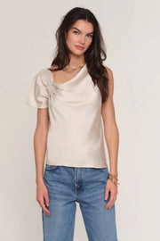 Woman wearing a satin cream top with draped neckline. 