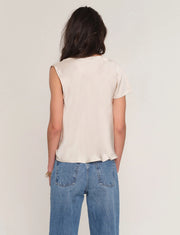 Woman wearing a satin cream top with draped neckline. 