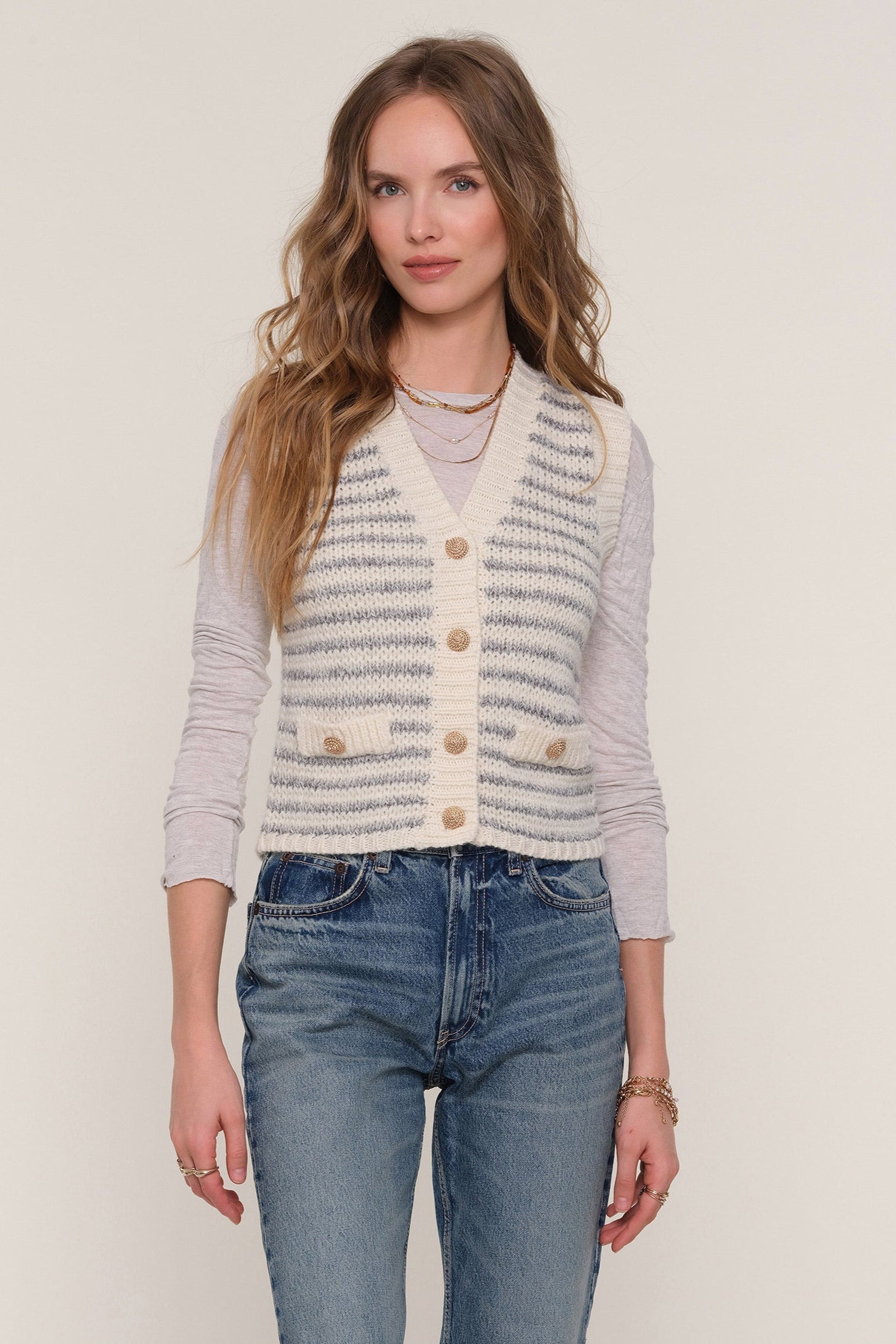 Front view of woman wearing a blue and white striped knit vest with gold hardware