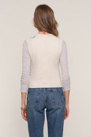 Back view of woman wearing a blue and white striped knit vest with gold hardware