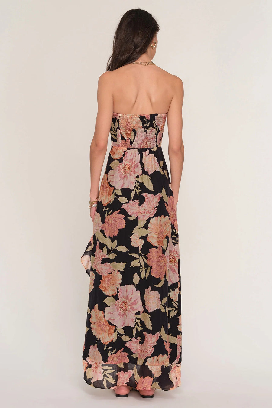 Woman wearing a floral strapless dress with a slit. 