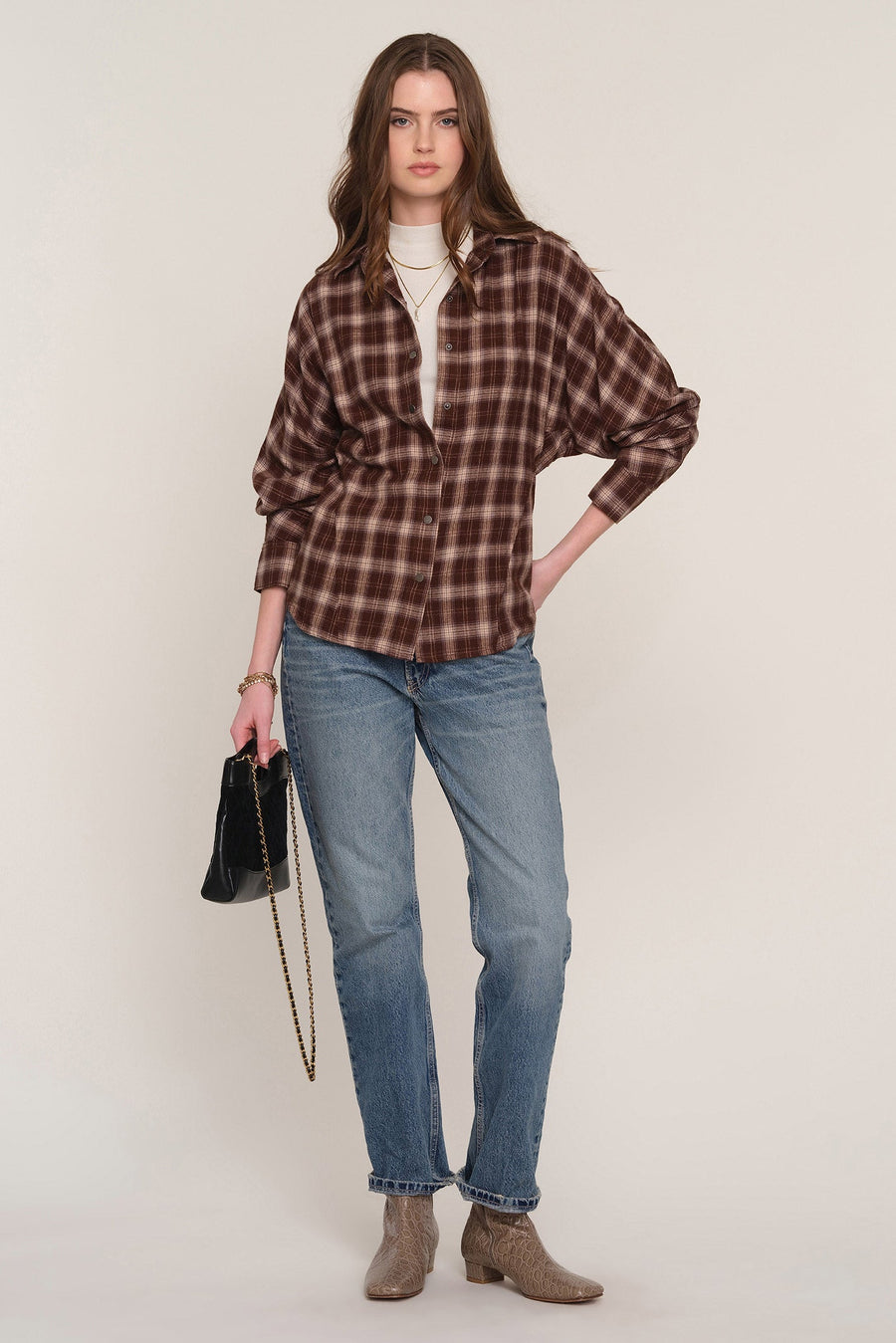 A woman modeling a brown and dark red plaid button-up shirt 