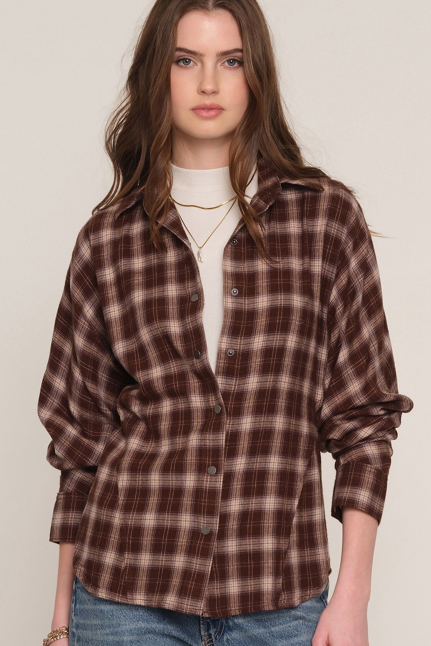 A woman wearing a brown and beige plaid button-up shirt 