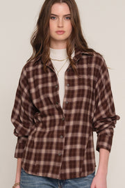 A woman wearing a brown and beige plaid button-up shirt 
