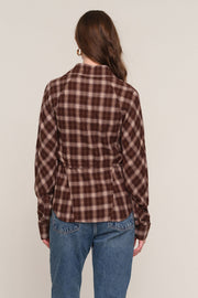 A woman viewed from the back wearing a brown and beige plaid long-sleeve shirt with a peplum waist, 
