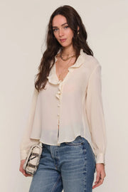 Front view of a woman wearing a cream blouse and blue jeans 