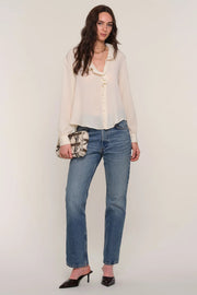 Full body shot of a woman wearing a cream blouse and blue jeans 