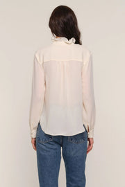 Back view of a woman wearing a cream blouse and blue jeans 