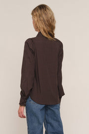 A woman shown from the back wearing a dark brown and black checkered long-sleeve button-up 