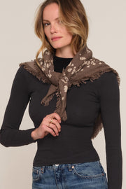 A woman wearing a brown and beige patterned fringed scarf 
