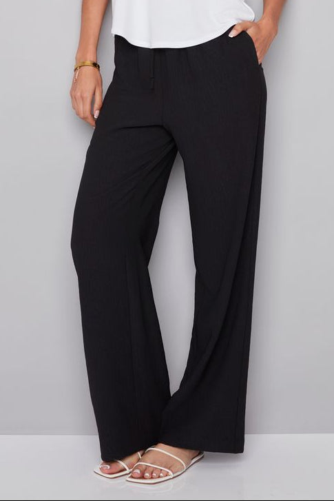 Woman wearing a white sleeveless top and black pants