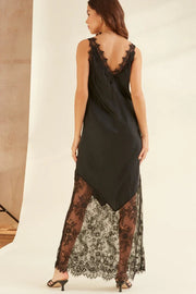 Woman wearing a black dress with lace detailing on a plain background