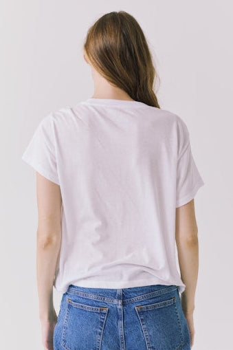 Back view of Woman wearing a white graphic tee shirt with a tropical graphic on the front
