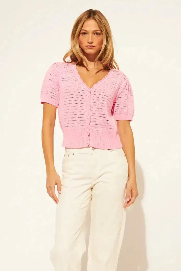 Woman wearing a bubblegum pink knitted button down short sleeve top