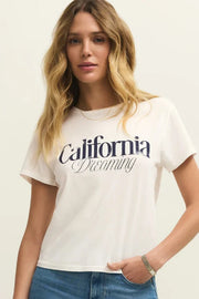 Woman wearing a white tee shirt with California dreaming graphic on front
