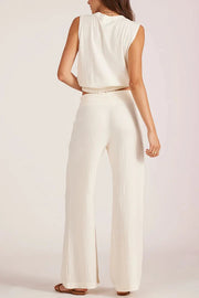 Woman wearing a wide leg beach pant in off white Back view