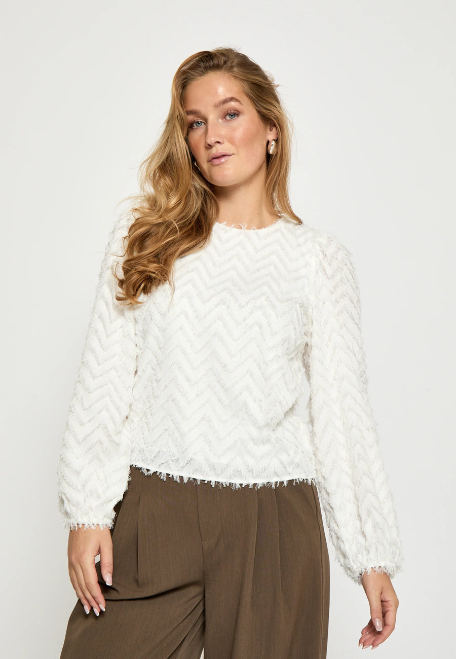 Woman wearing a white blouse with zig zag textured detail allover