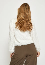 Woman wearing a white blouse with zig zag textured detail allover Back view