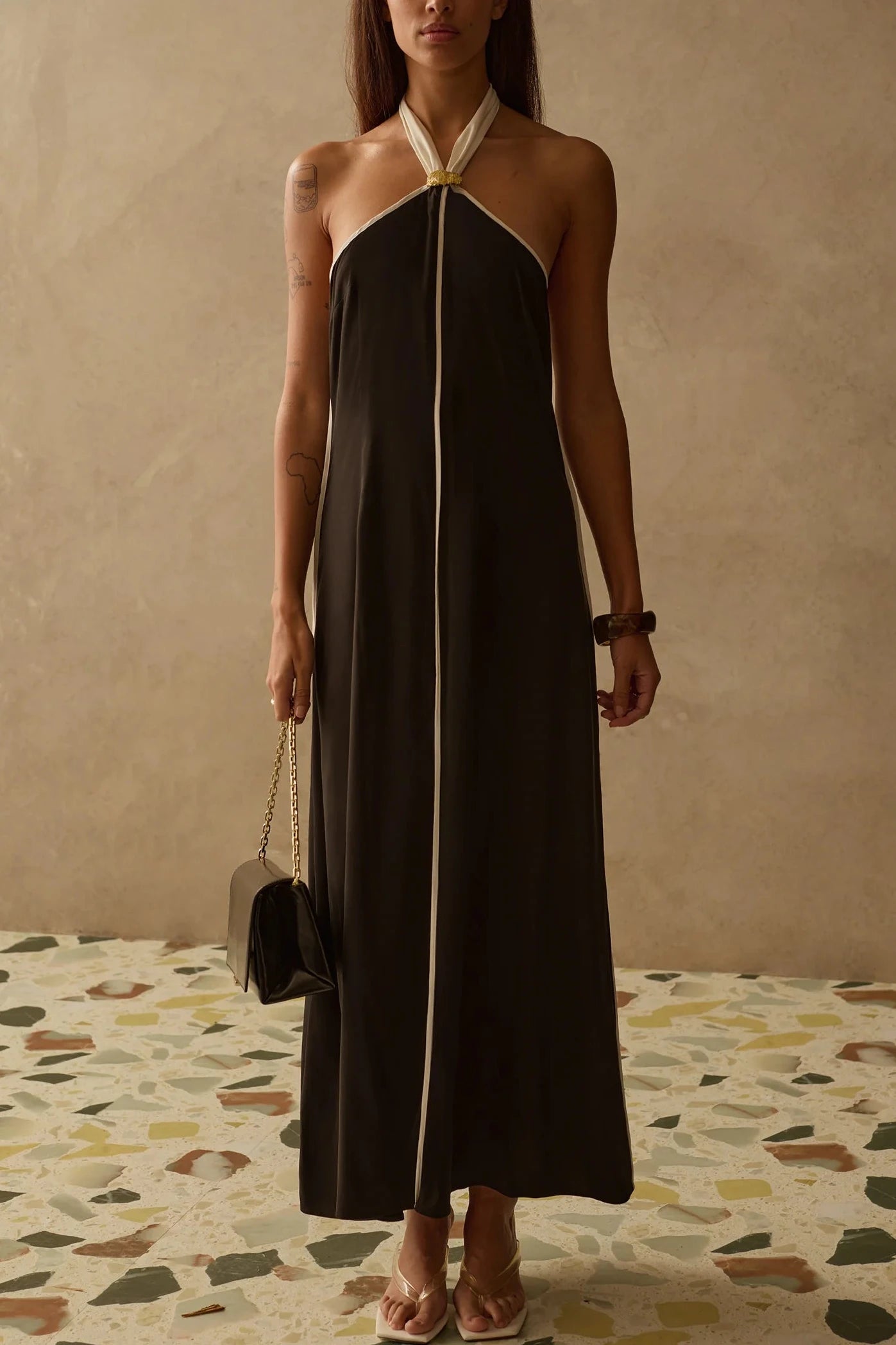 Woman wearing a halter neck dress in black with white trim 