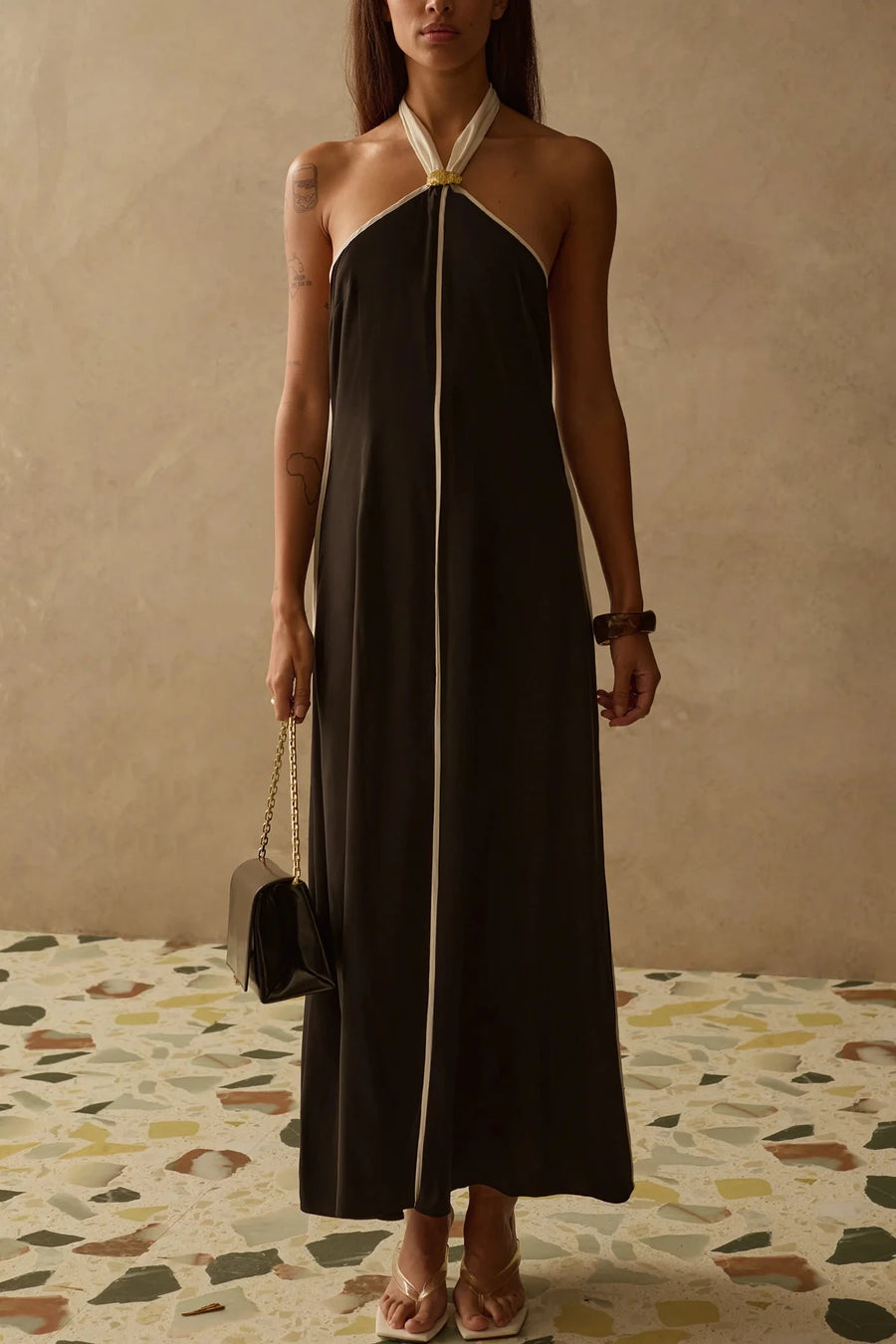 Woman wearing a halter neck dress in black with white trim 