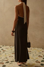 Back view of Woman wearing a halter neck dress in black with white trim 