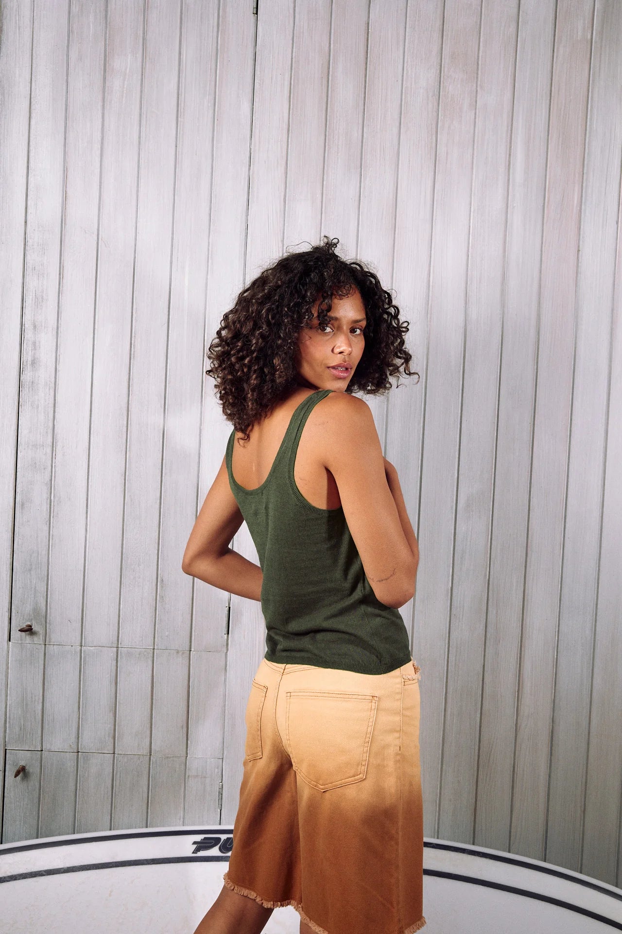 Back view of Woman wearing a dark green knit tank top