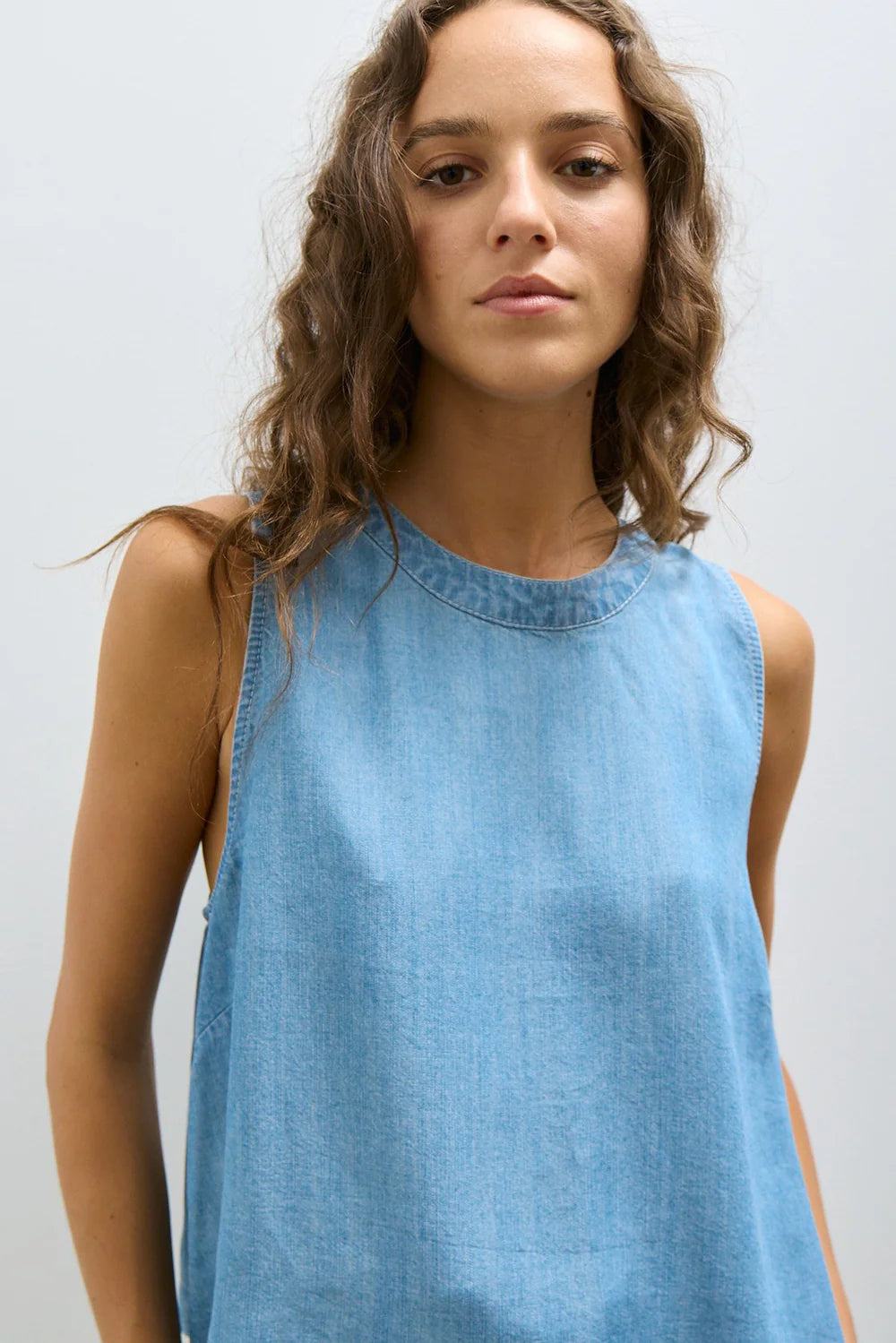 Woman’s wearing a medium denim blue sleeveless top