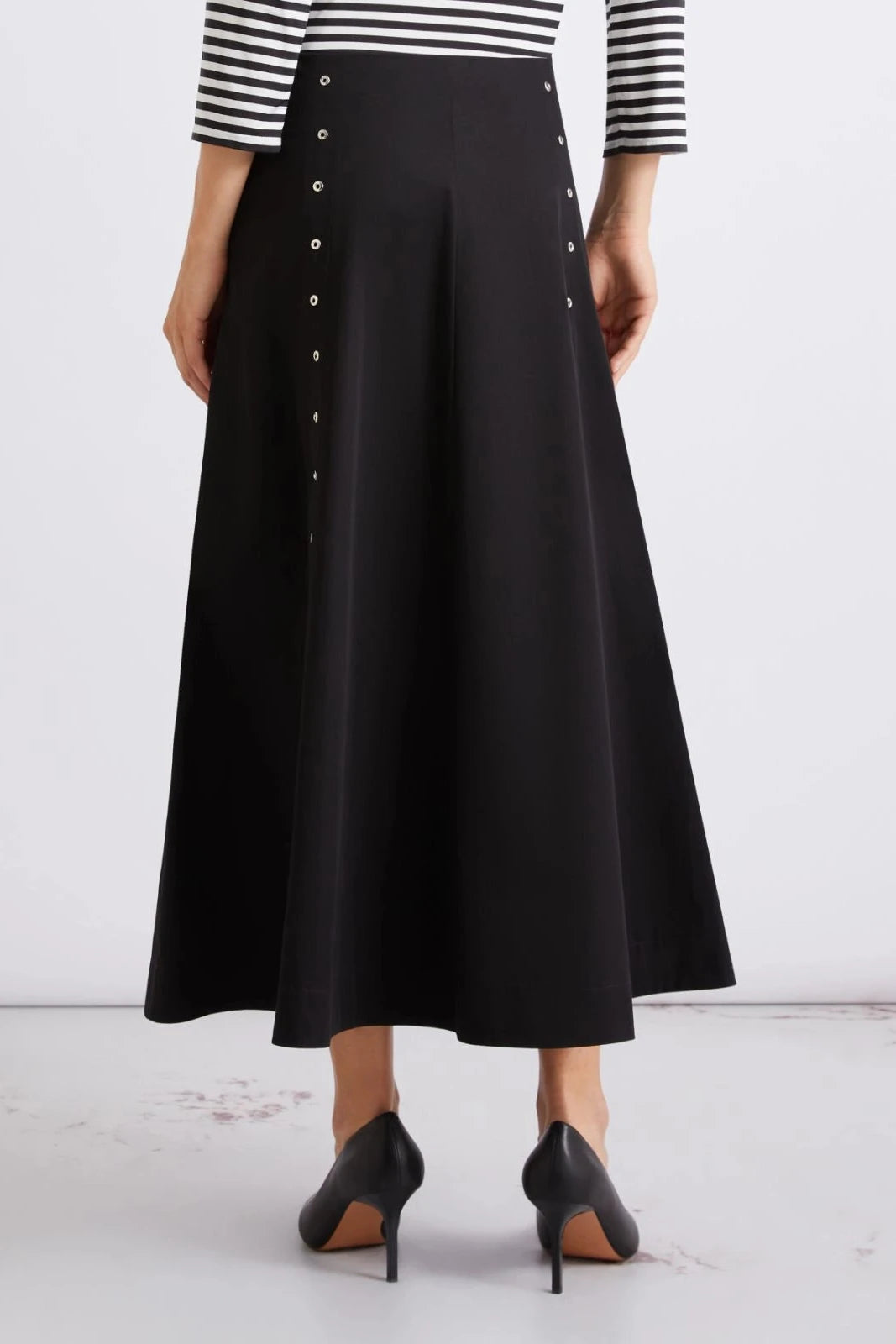 Close up of woman wearing black midi skirt with metal button details