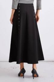 Close up of woman wearing black midi skirt with metal button details