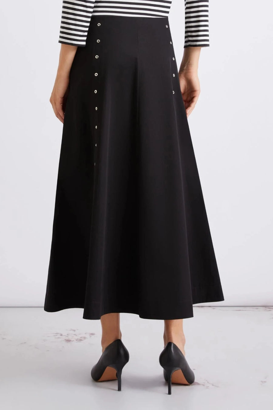 Close up of woman wearing black midi skirt with metal button details