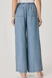 Back view of Woman wearing a pair of indigo flowy pants With drawstring waistband