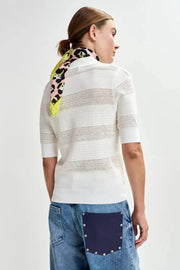 Backview of woman wearing a white knit polo with little bow details allover