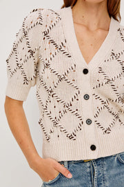 Close up view of the shoulder and neck of a woman wearing an argyle textured  wool blend cardigan 