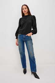 wearing a black sweatshirt with lace detailing and cuffed popplin  sleeves and blue jeans