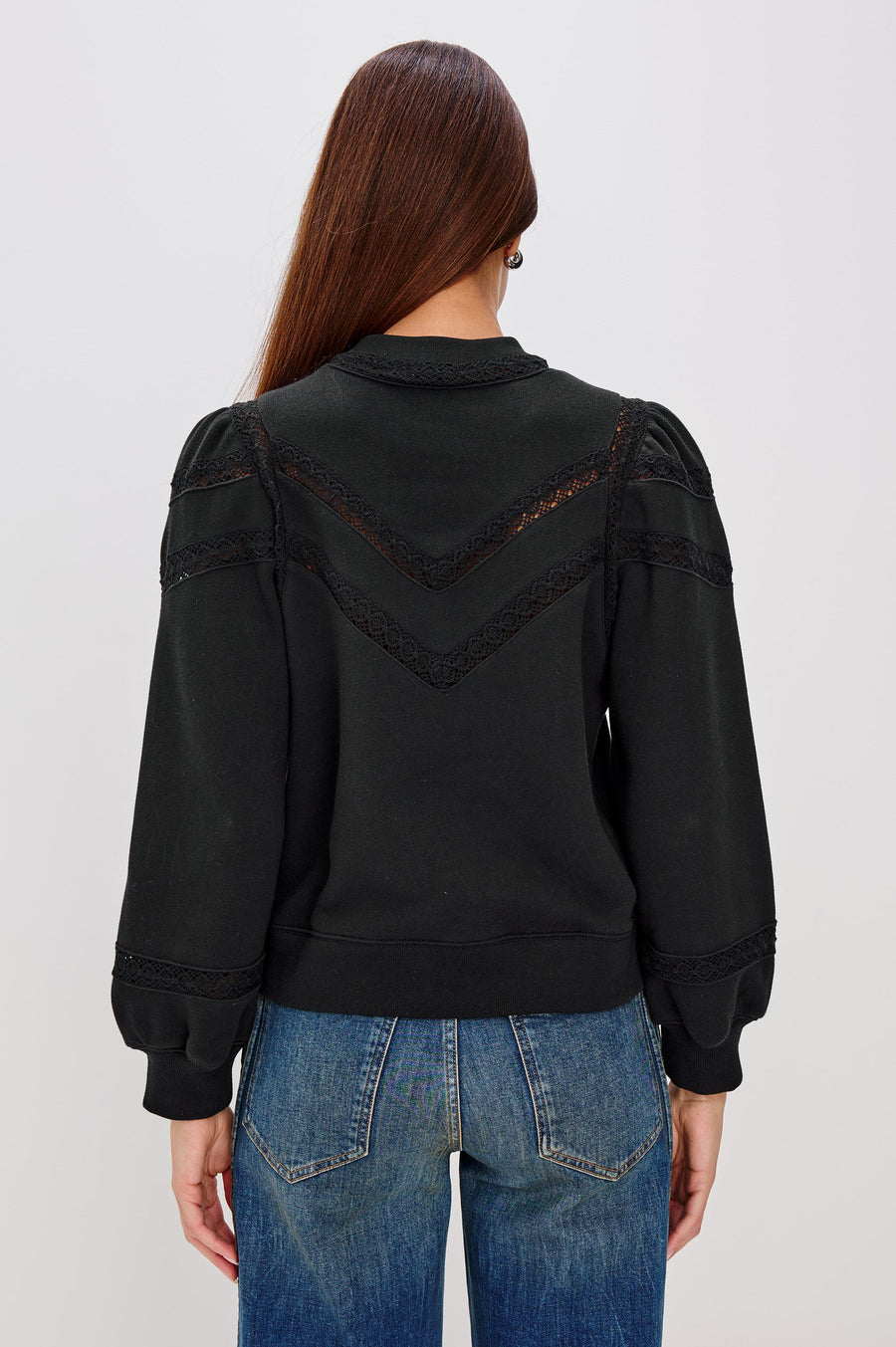 woman wearing a black sweatshirt with lace detailing and cuffed poplin  sleeves