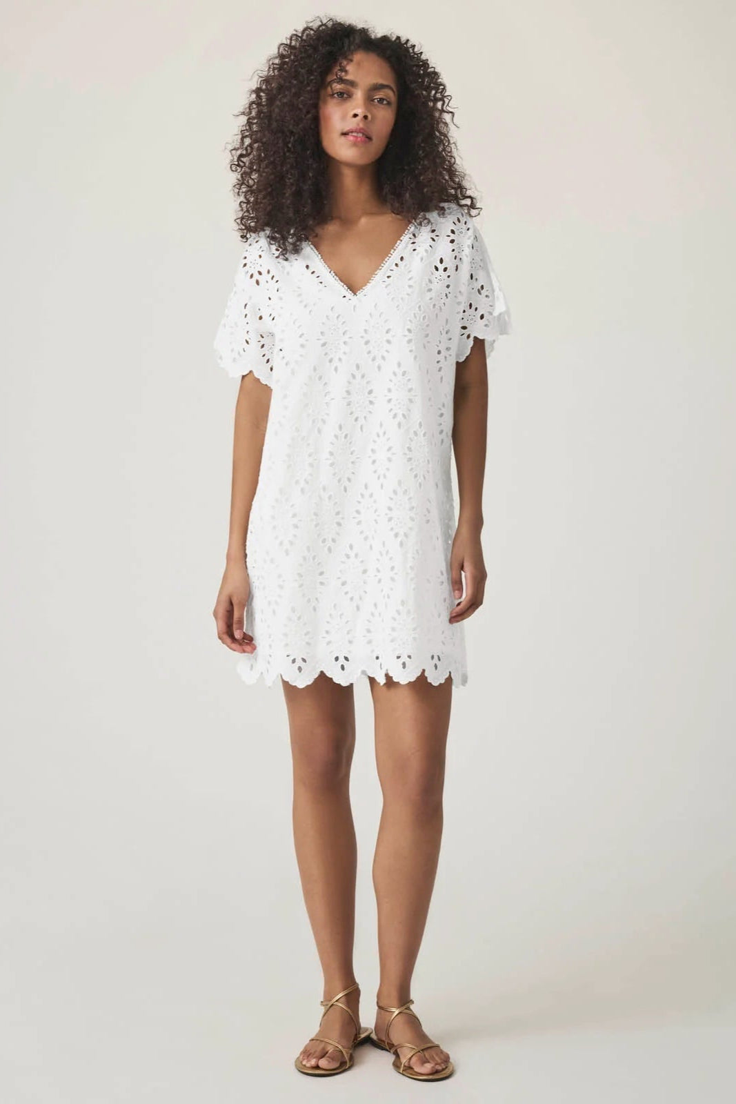 Woman wearing a white lace eyelet mini dress scalloped hem