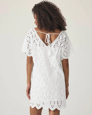 Woman wearing a white lace dress against a plain background