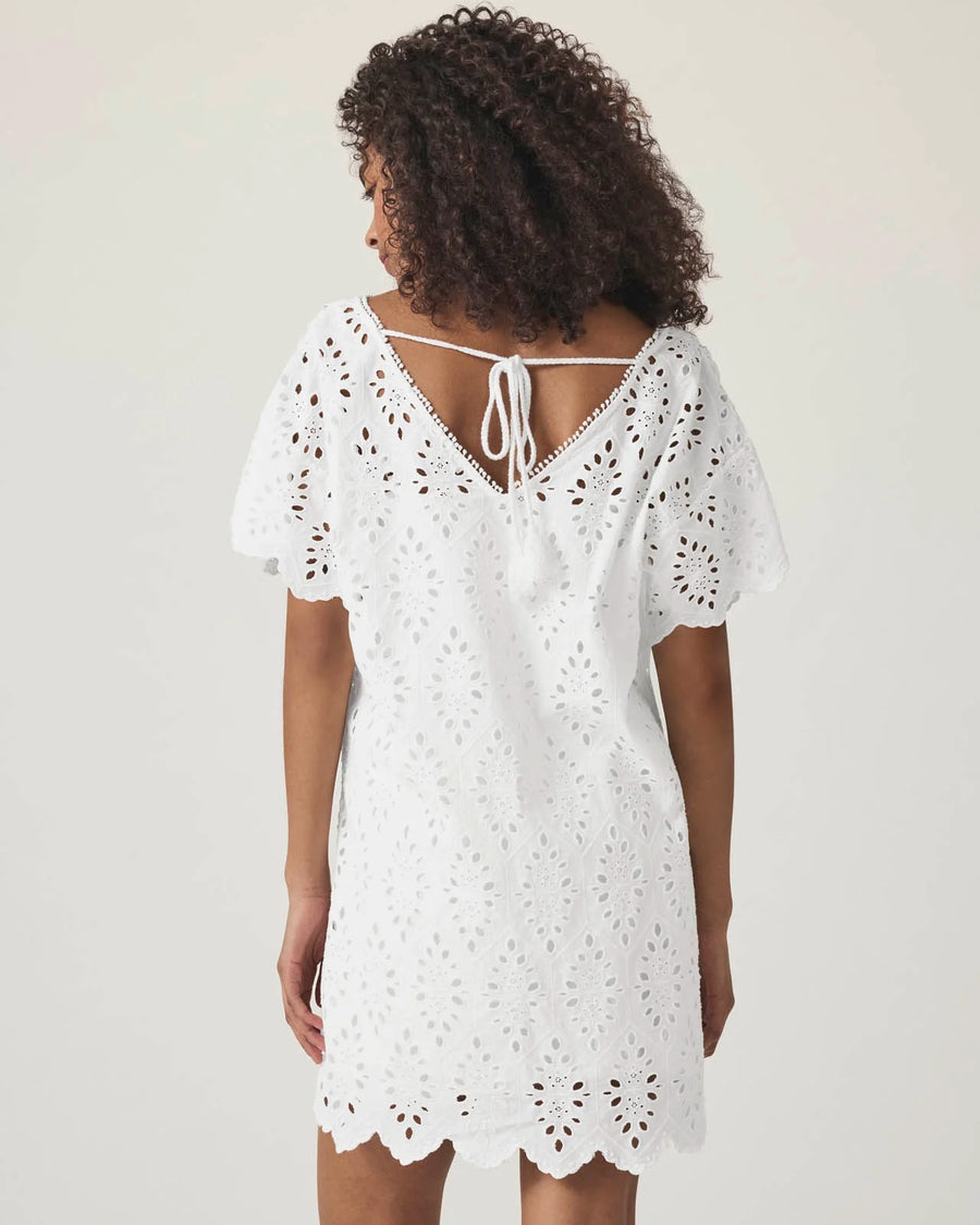 Woman wearing a white lace dress against a plain background